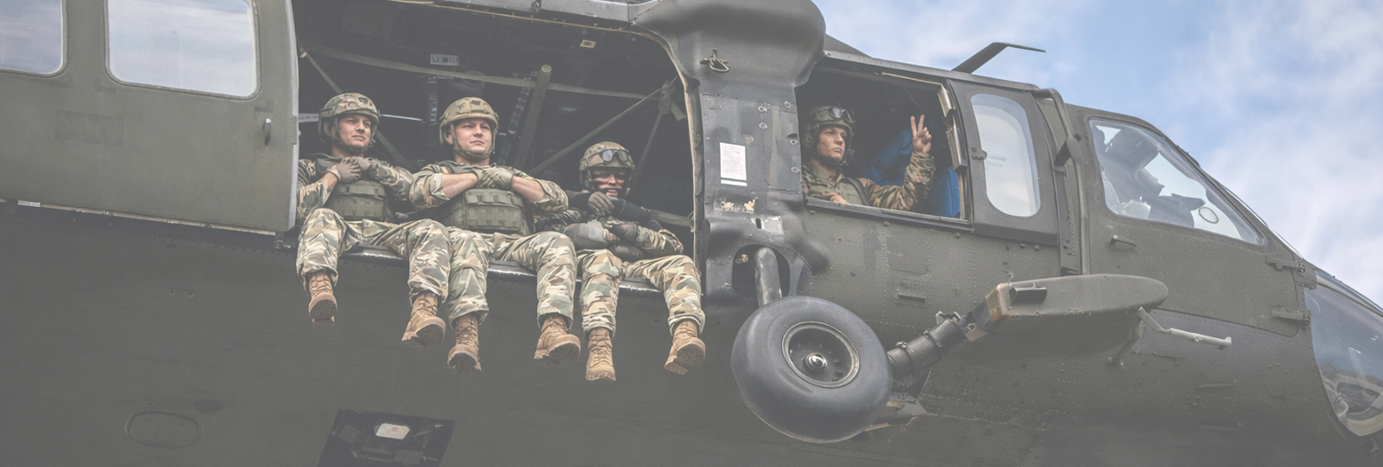 Soldiers seated in the open door of a helicopter